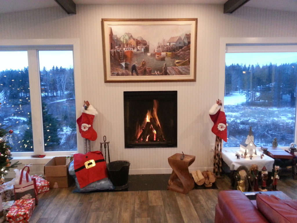 Living room with Christmas decorations, fireplace, and snowy outdoor view.
