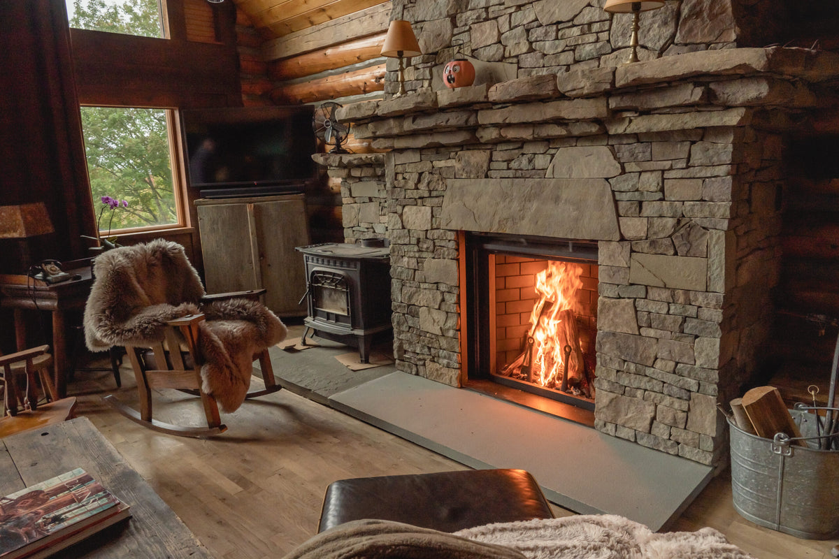 Cozy living room with stone fireplace, wooden chair, and television.