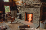 Cozy living room with stone fireplace, wooden chair, and television.