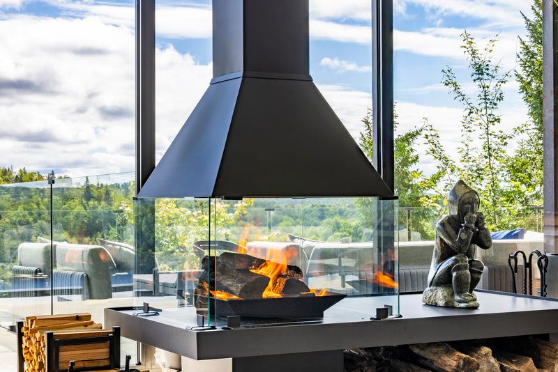 Close-up of a Don-Bar central wood-burning fireplace and black steel hood