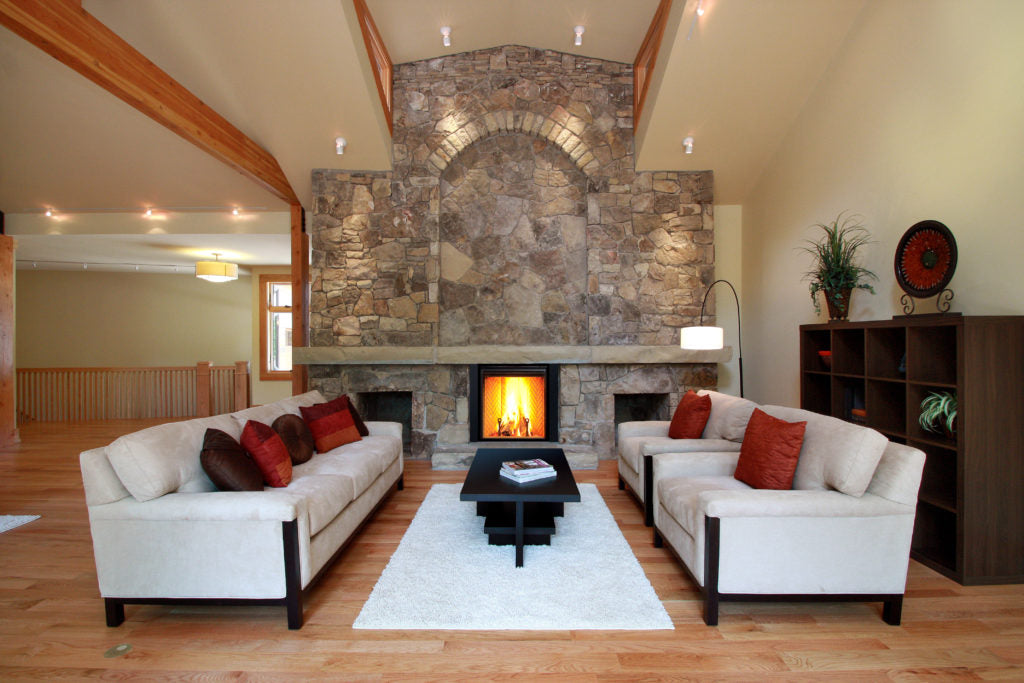 Living room with stone fireplace, white sofas, and wooden floor.
