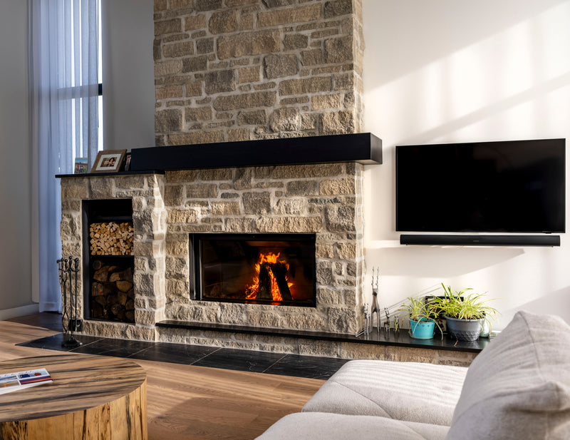 Stûv 21-125 wood fireplace integrated into a stone wall in Rigaud